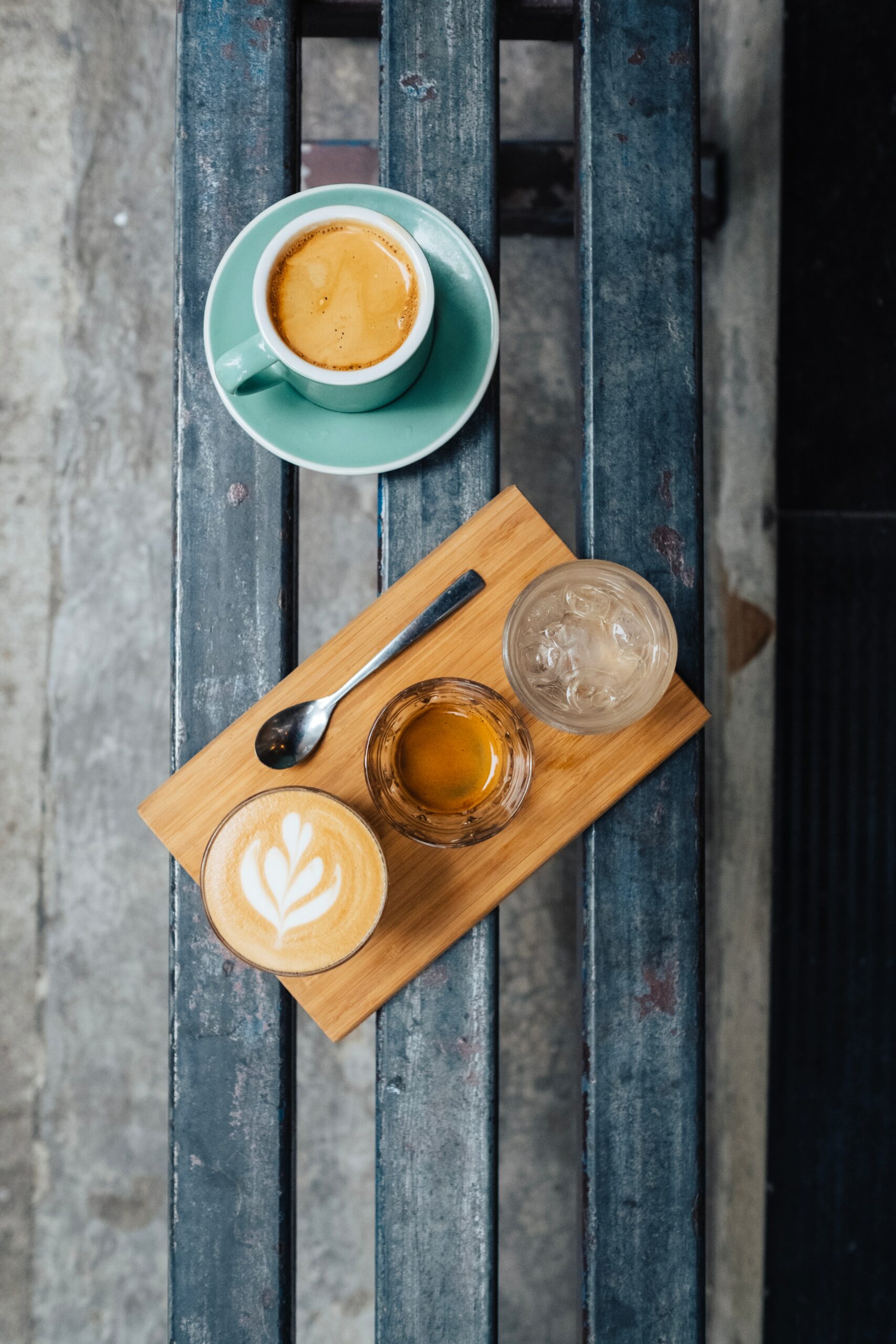 A cup of coffee and a coffee mug placed on a wooden bench